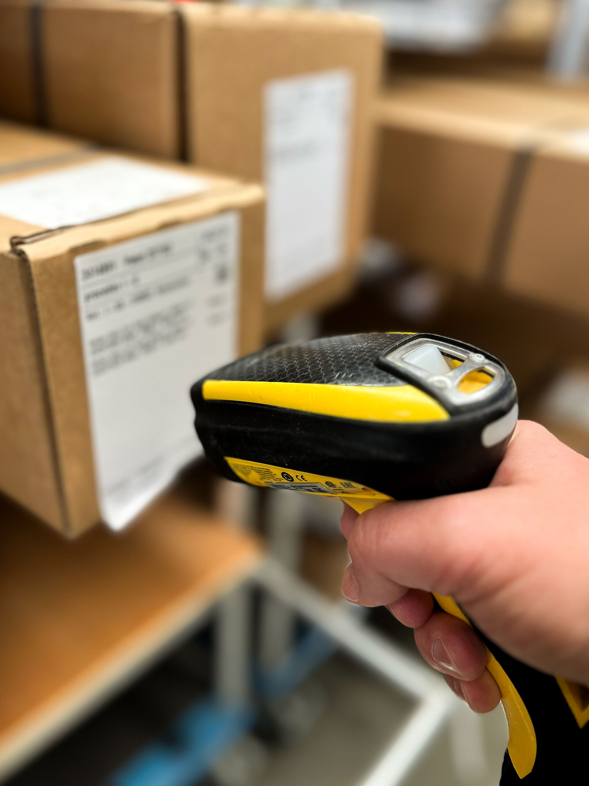 Hand mit einem Handscanner, der ein Paket mit Label scannt.